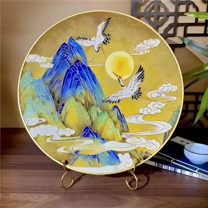 A circular cloisonne silk enamel diy kit plate with blue and green mountains, white cranes, and golden background decorbites