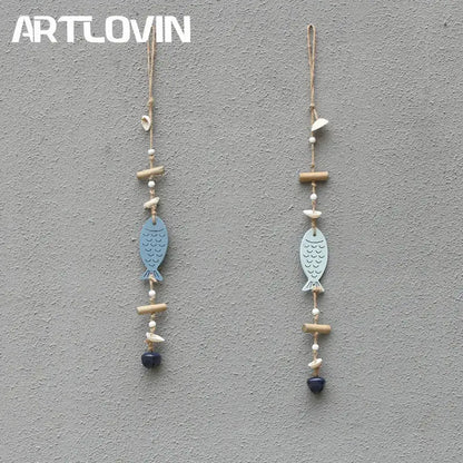 Two light blue coastal fish drift wood bells with scalloped fins hanging from natural twine with white beads and charms