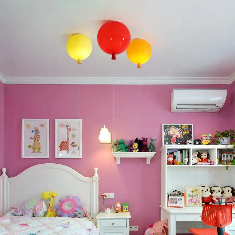 Three colorful balloon ceiling lights in red yellow and orange decorate a bedroom or nursery by decorbites