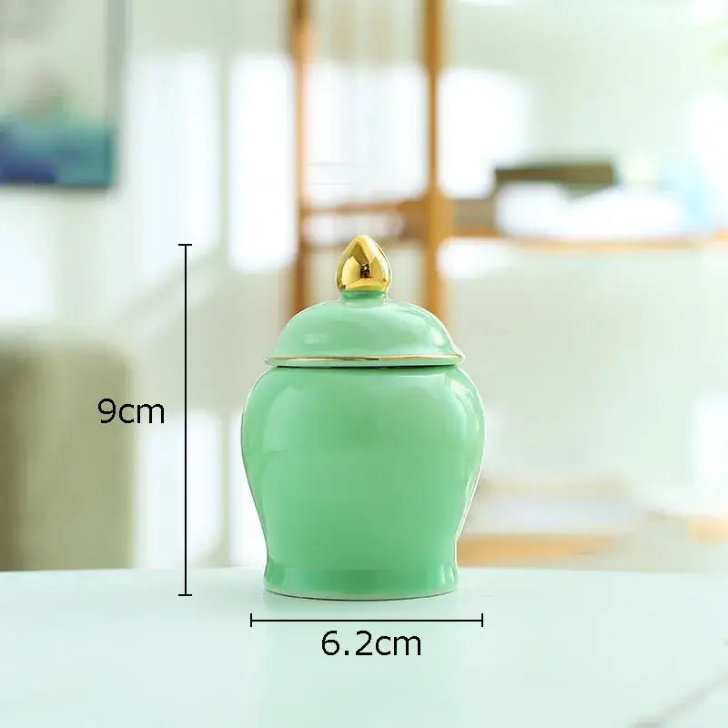 Glossy mint-green ceramic storage jar with gold-trimmed lid and golden teardrop finial for kitchen tea caddy use