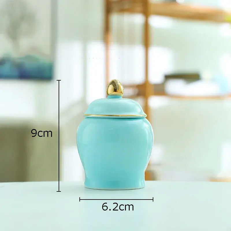 A light blue ceramic storage jar with a gold-trimmed lid and golden knob for kitchen tea caddy use