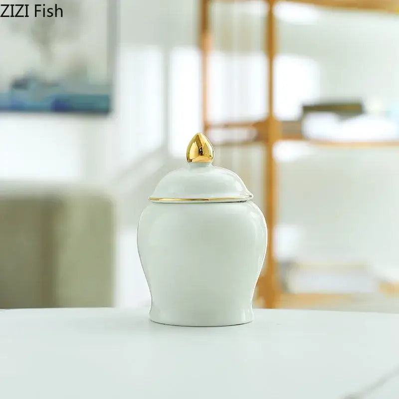 White ceramic storage jar with gold-trimmed lid and golden teardrop finial for kitchen tea caddy use