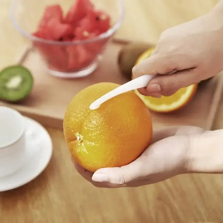 White plastic decorbites citrus zester peeler removing zest from bright orange in colorful 4-piece zester peeler knife set