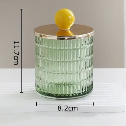 A translucent green glass tea canister with vertical ridges and a gold-toned storage jar lid with yellow knob