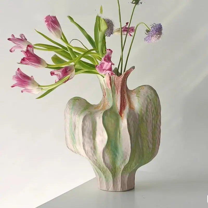 A colorful irregular ceramic petal vase with organic wavy contours and mottled green pink off-white glaze for living room decor