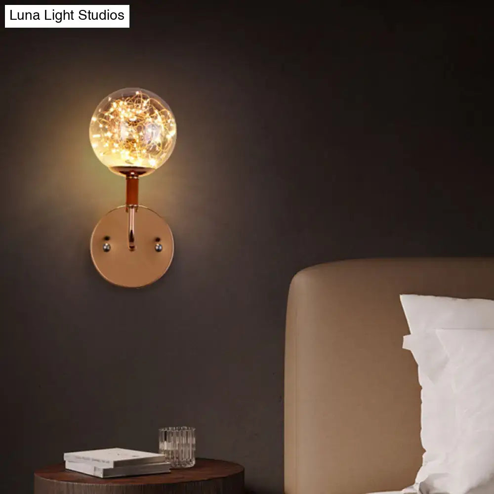 Contemporary amber glass direct wired electric bedroom wall sconce with warm-toned spherical glass globe and copper base