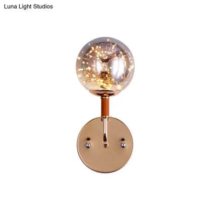 Contemporary rose gold direct wired electric bedroom wall sconce with clear amber glass globe housing warm fairy lights