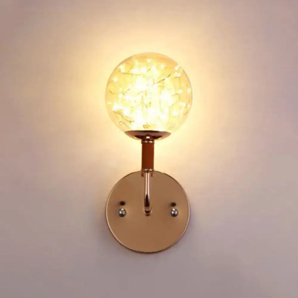 Contemporary amber glass direct wired electric bedroom wall sconce with warm-toned crackled glass globe and rose gold metal mounting