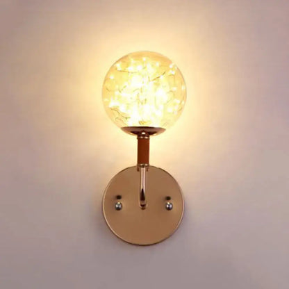 Contemporary amber glass direct wired electric bedroom wall sconce with warm-toned crackled glass globe and rose gold metal mounting