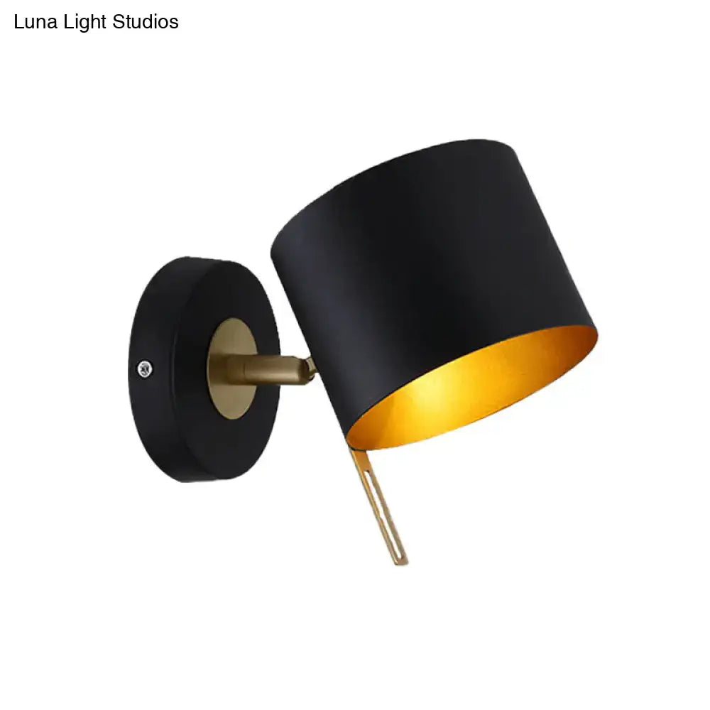 Contemporary black and gold metal drum wall sconce featuring a cylindrical design with brass accents for bedroom lighting