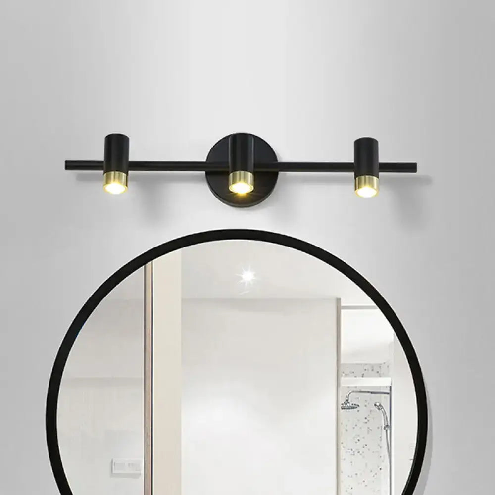 Contemporary black and brass three-light vanity light wall sconce with sleek cylindrical bulbs and adjustable color temperature