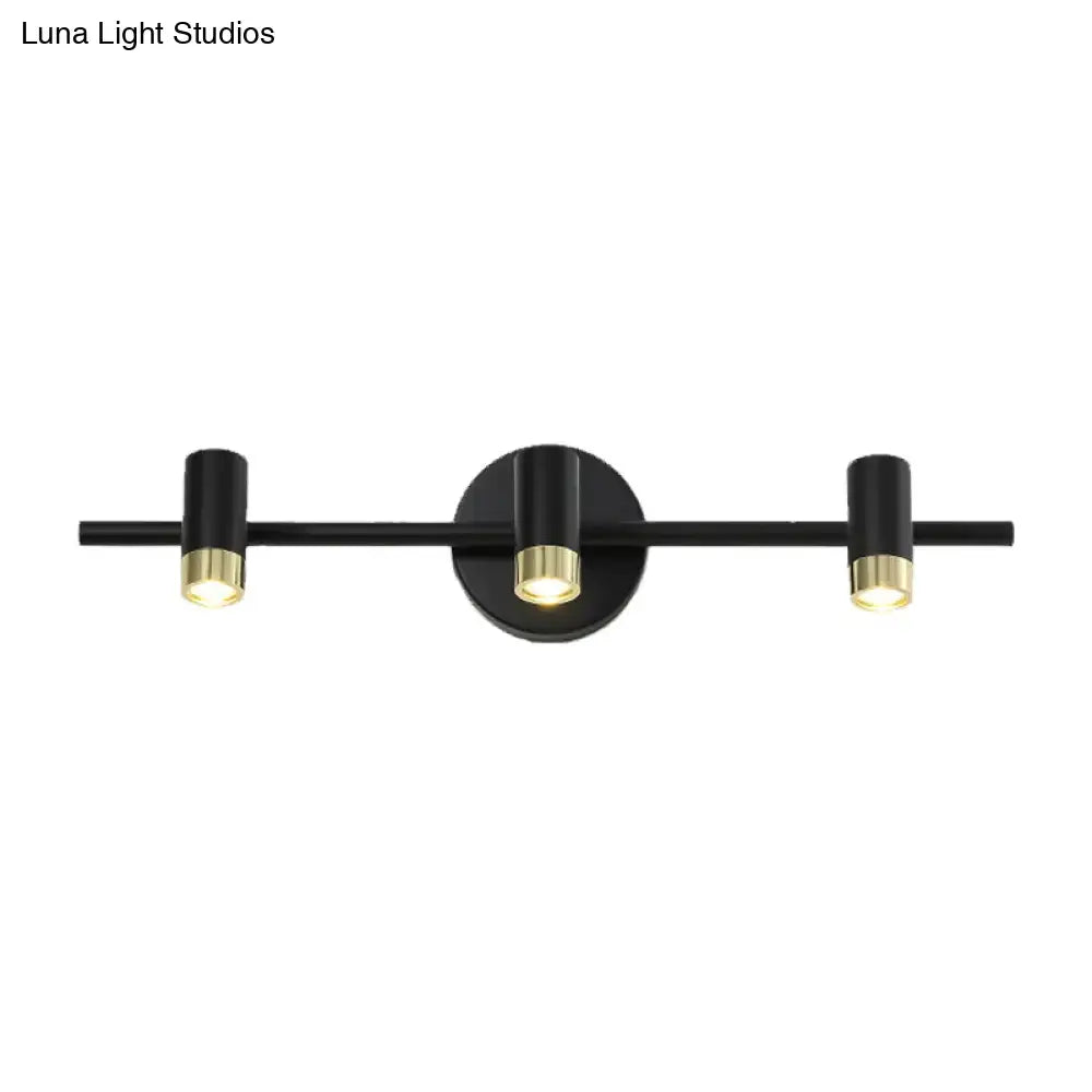 Contemporary black and brass three-light wall sconce with sleek cylindrical fixtures ideal for vanity light color temperature