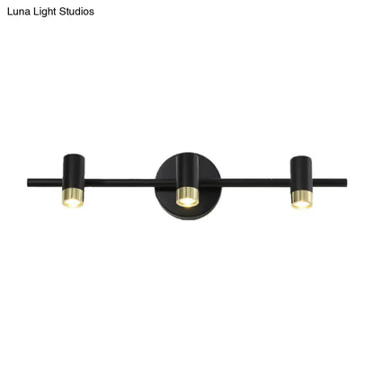 Contemporary black and brass three-light wall sconce with sleek cylindrical fixtures ideal for vanity light color temperature