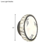 Contemporary black circular wall light with clear crystal trim and decorative swirl patterns on white diffuser for bedroom