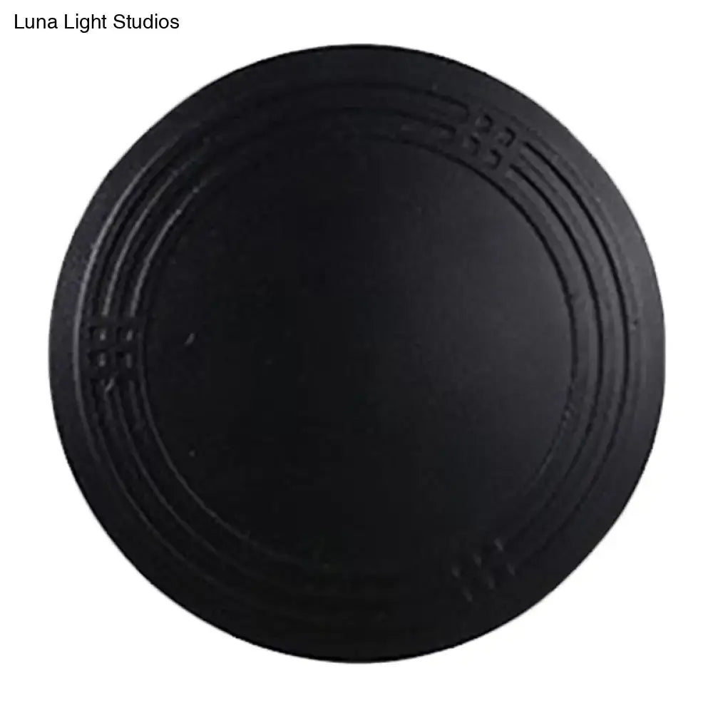 Contemporary black flower wall sconce light featuring a black circular coaster with embossed geometric patterns for bedroom use