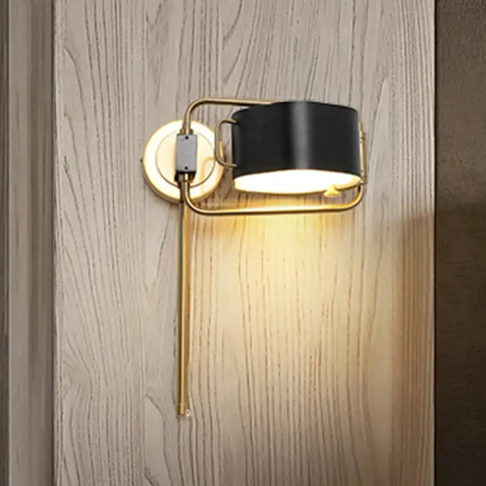 Contemporary black and gold drum wall sconce with cylindrical shade and warm acrylic led light mounted on wood wall
