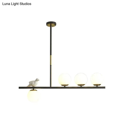 DecorBites contemporary linear branch dining pendant light in black and brass with cream glass bulbs and ceramic bird decor