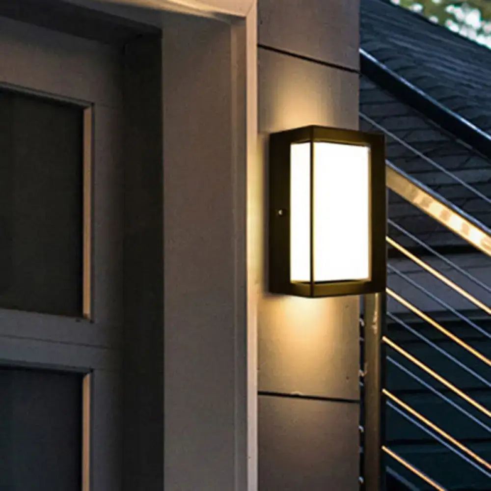Contemporary black led wall lamp with frosted glass panel emitting warm light for outdoor courtyard use