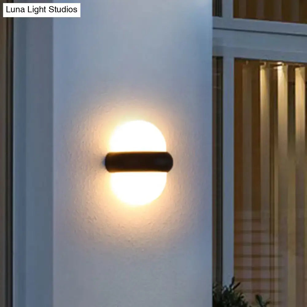 Contemporary black semi-sphere wall sconce with warm-toned circular light and sleek cylindrical base for outdoor area use