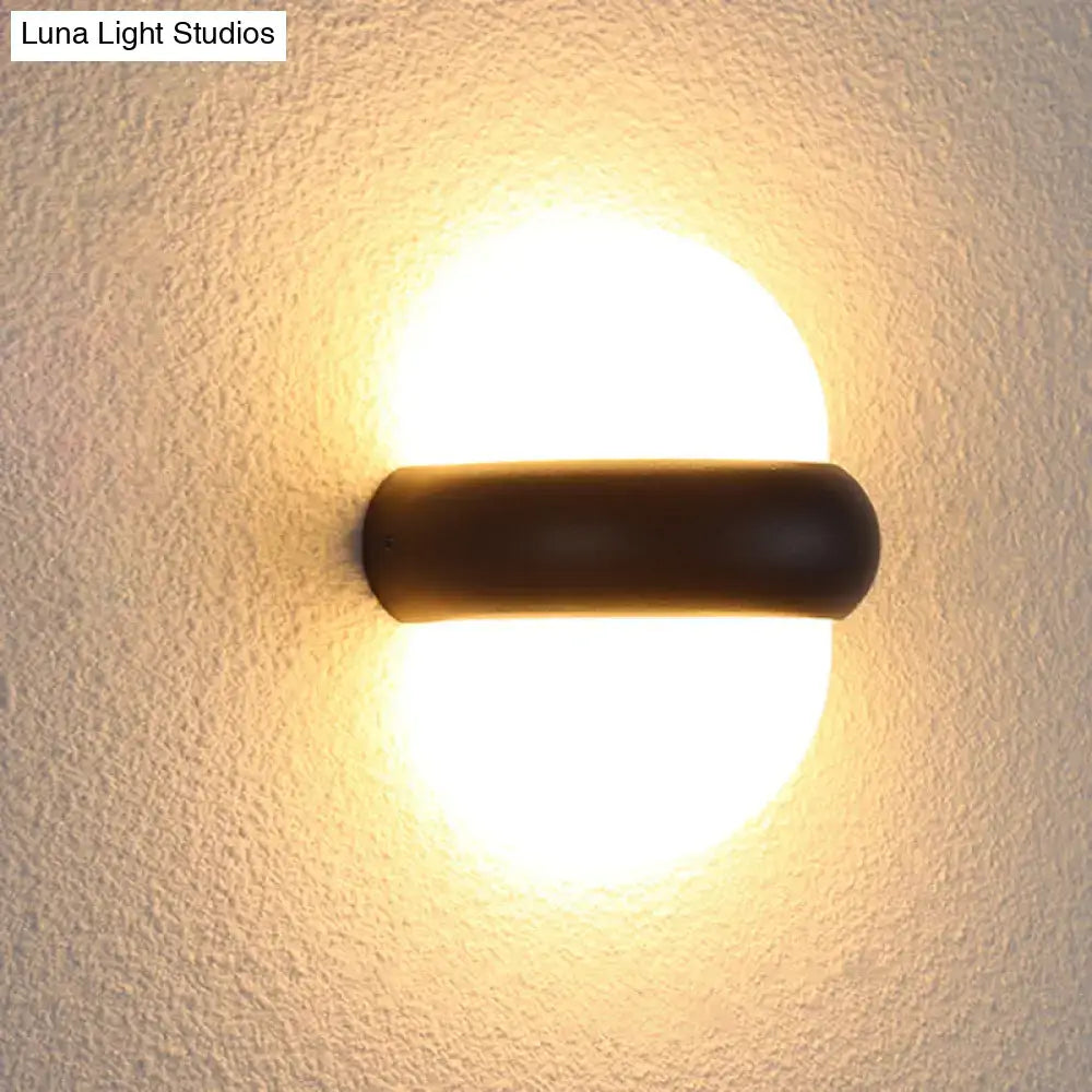 Contemporary warm-toned circular wall sconce with dark bronze cylindrical fixture for outdoor area wall lamp use