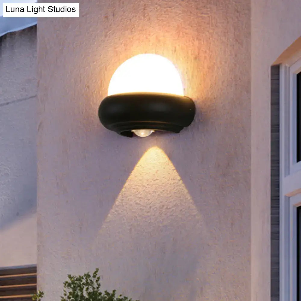 Contemporary black semi-sphere wall sconce with frosted glass dome emits warm light for outdoor area wall lamp