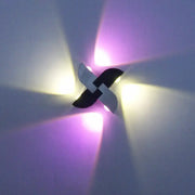 Contemporary black and silver windmill rgb wall sconce with black and white pinwheel design emitting warm yellow and purple light