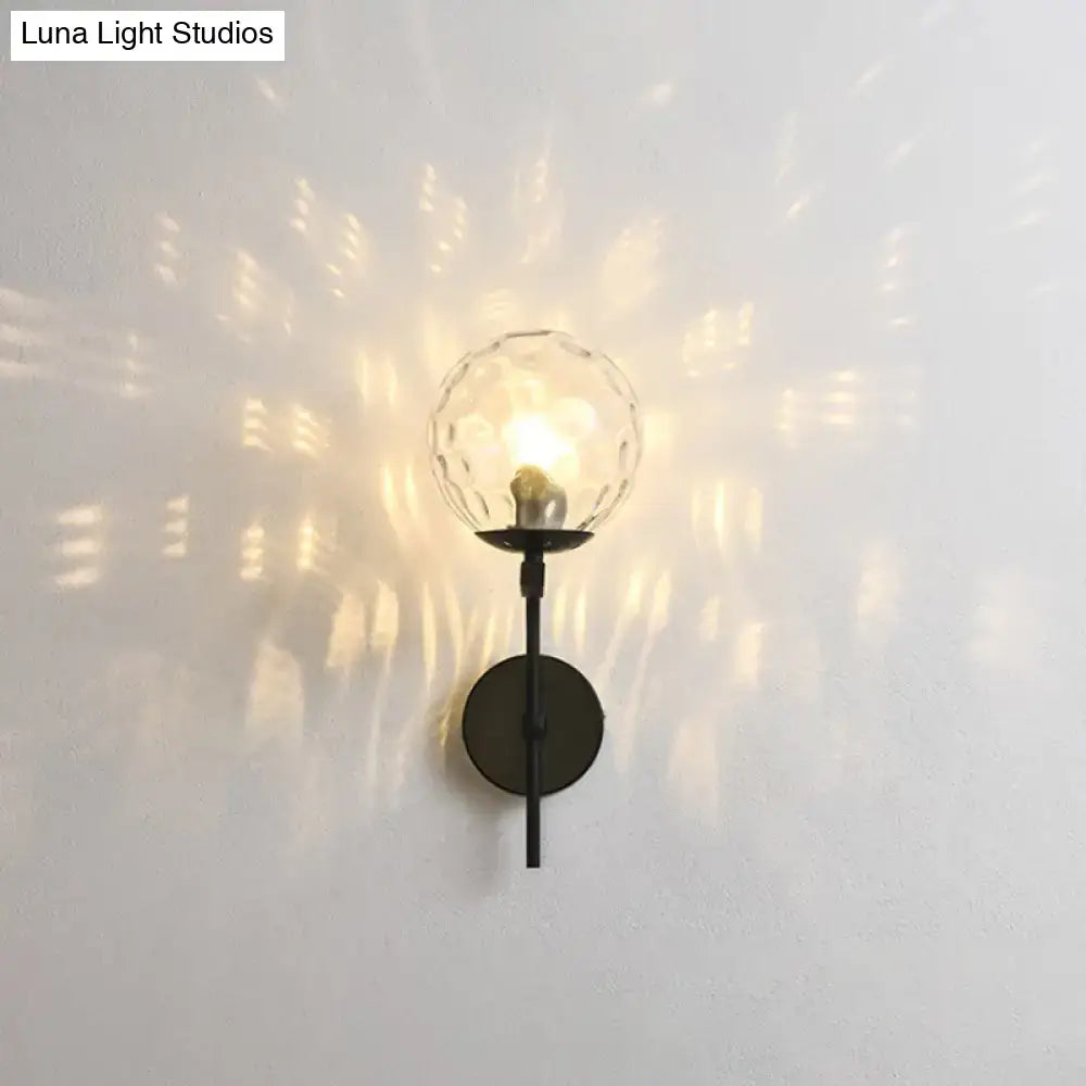 A sleek black metal wall mount lighting with a faceted clear glass globe for contemporary bedroom use