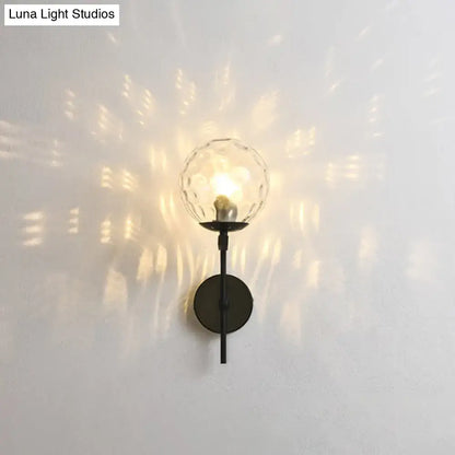 A sleek black metal wall mount lighting with a faceted clear glass globe for contemporary bedroom use
