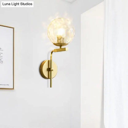 Contemporary gold-toned wall mount lighting with a textured translucent glass globe for bedroom use