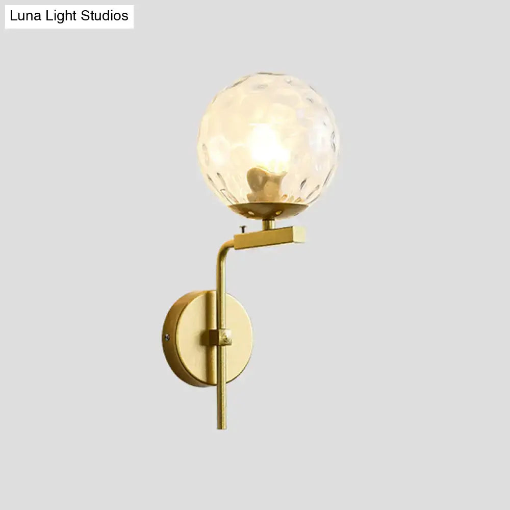 Gold-finished wall mount lighting with a textured spherical glass globe for contemporary bedroom use