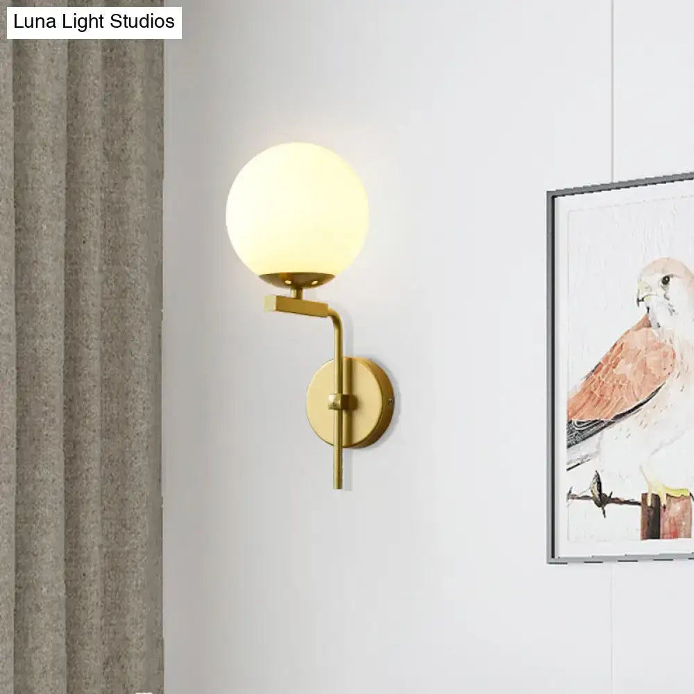 Gold-toned wall mount lighting with frosted glass globe in contemporary black sphere design for bedroom use