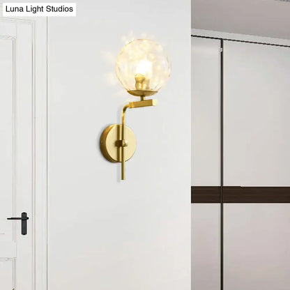 Gold-toned wall mount lighting with a textured frosted glass globe for contemporary bedroom use