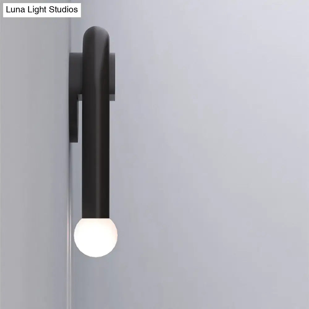 Contemporary black u-shaped light fixture with a minimalist cylindrical body and glowing spherical bulb wall sconce