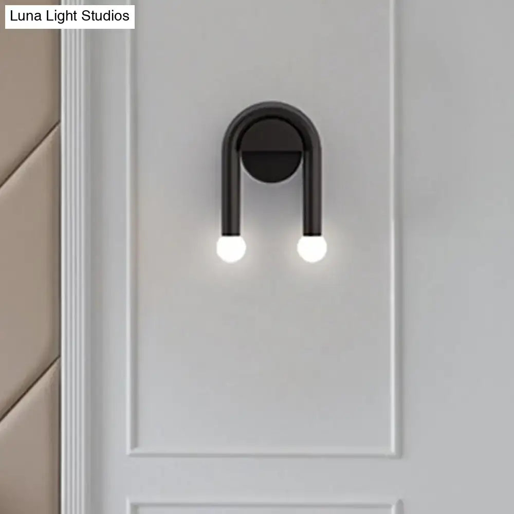 Contemporary black u-shaped light fixture bedroom wall sconce with two glowing spherical bulbs and sleek design