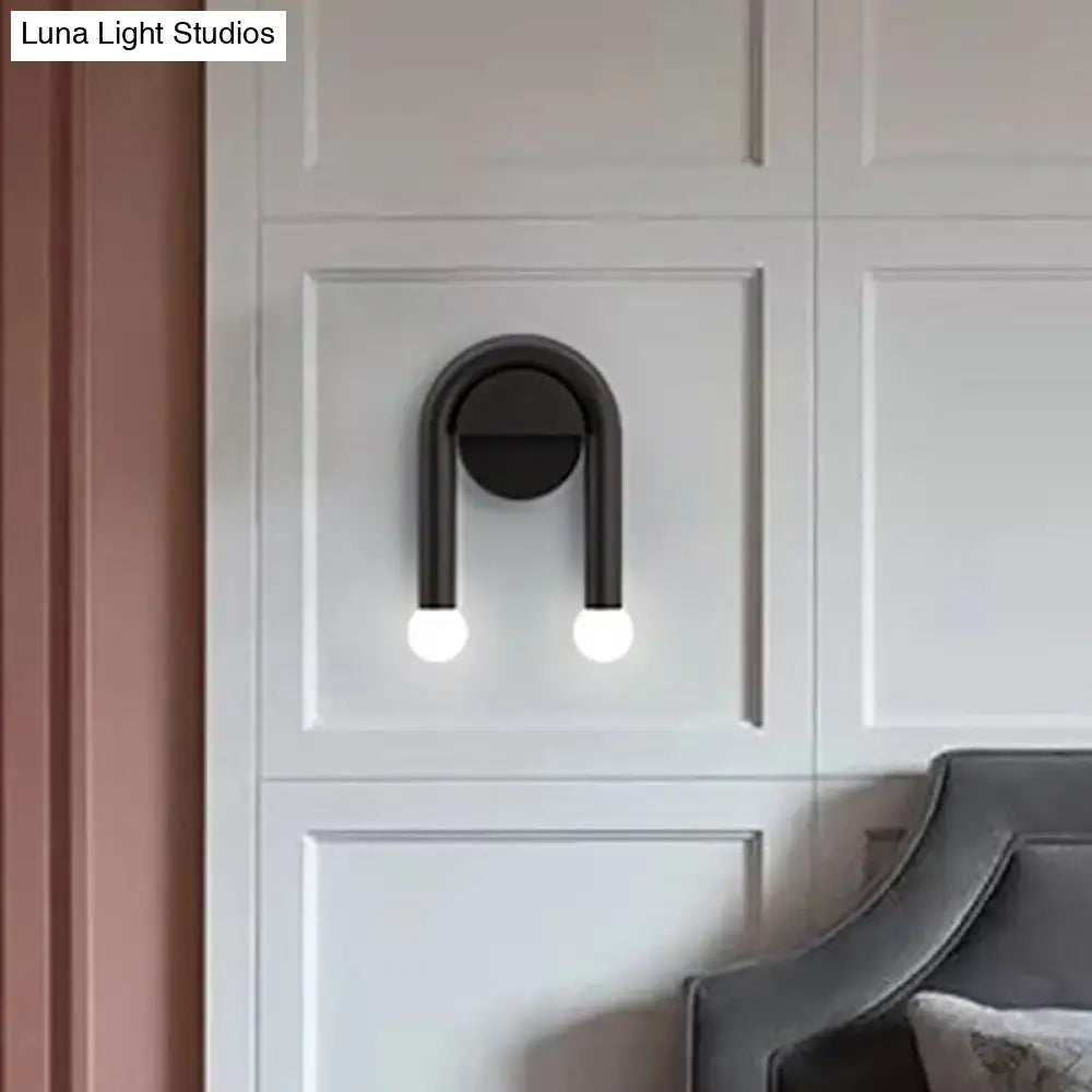 Contemporary black u-shaped light fixture wall sconce with two glowing spherical bulbs for bedroom lighting