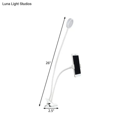 Contemporary black and white flexible led desk lamp with white gooseneck, circular led light head, and phone clamp for bedroom use