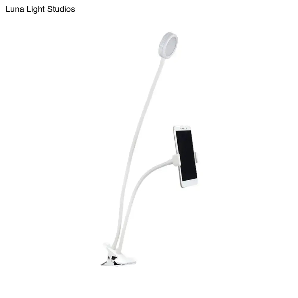 Contemporary black and white flexible led desk lamp with white gooseneck, circular light head, and phone clamp for adjustable illumination