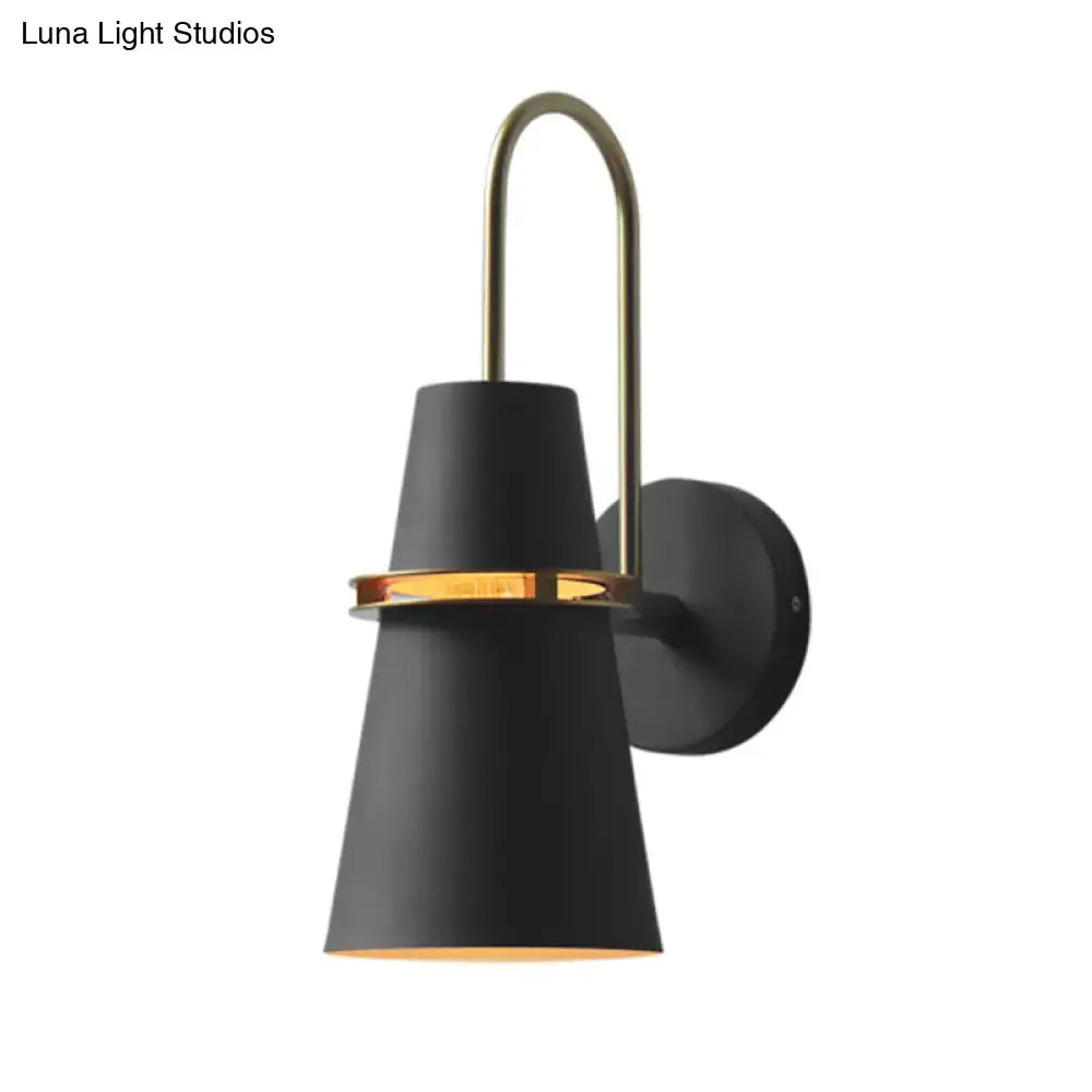 Contemporary black matte wall sconce light with brass curved arm and accent ring for bedroom lighting fixture