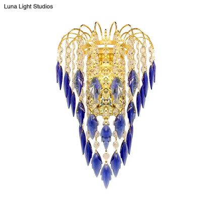 Contemporary brass wall lamp with golden chandelier design and cascading blue and clear crystal droplets for extra light