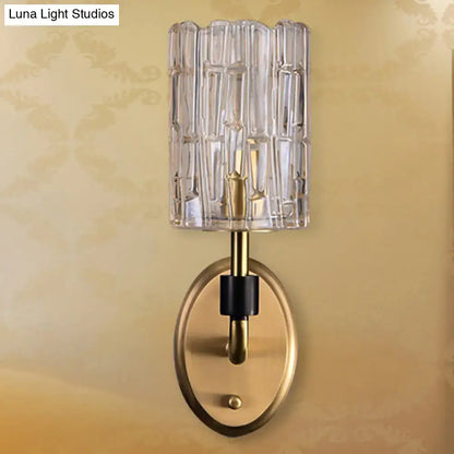 Contemporary brass bedside wall sconce with clear crystal shade and vertical ribbed glass texture for bedroom use