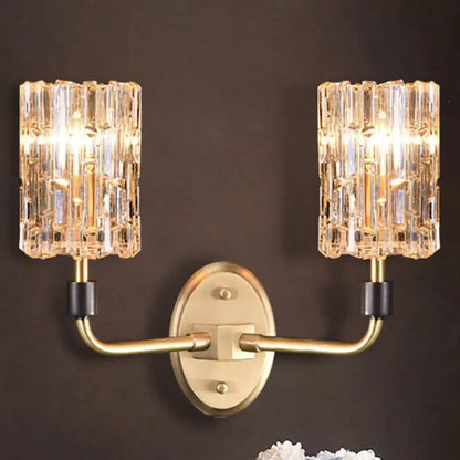 Contemporary gold-toned bedside wall sconce with clear crystal shade and two crystal-encrusted cylindrical shades