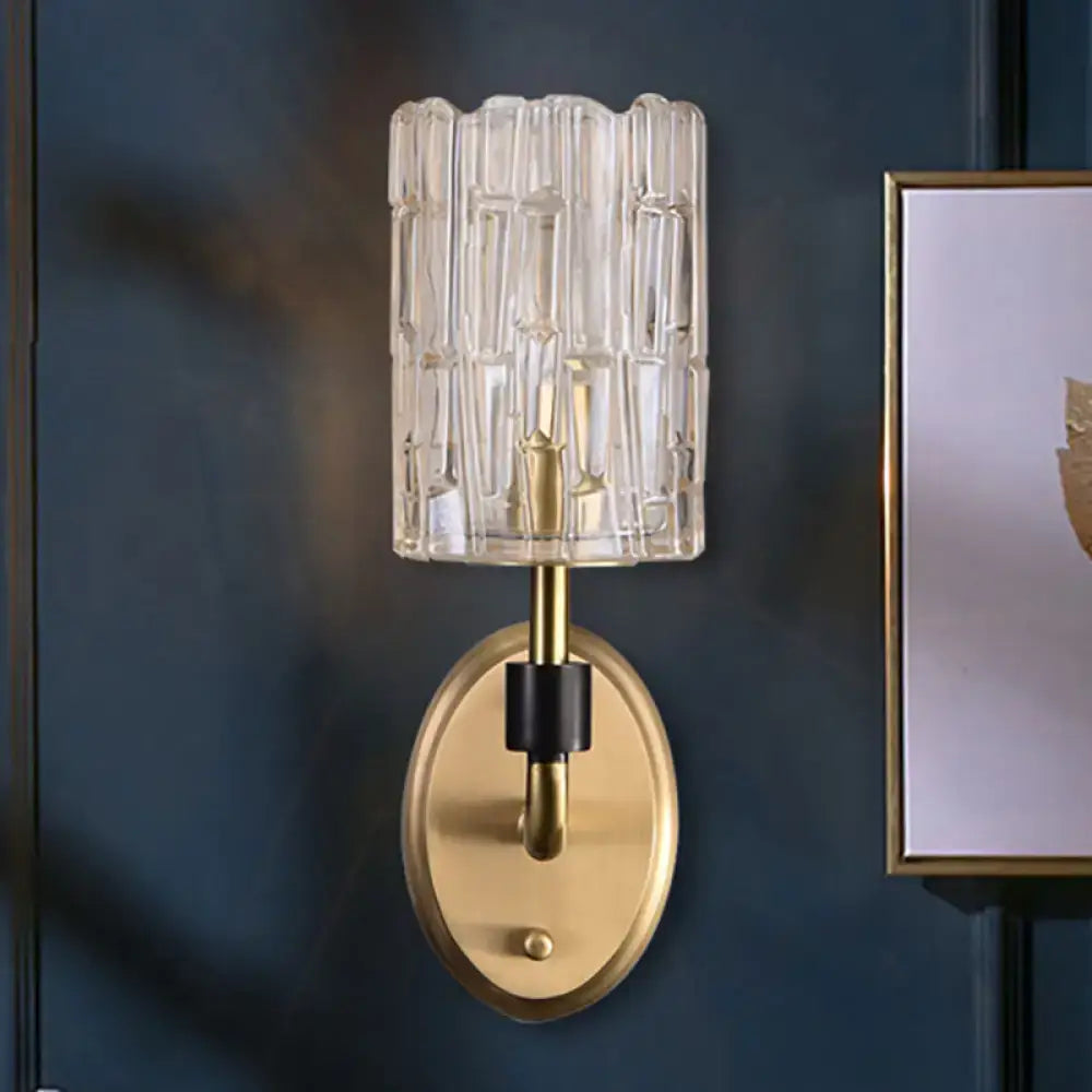 Contemporary brass bedside wall sconce with clear crystal shade and vertical ridged glass texture for bedroom use