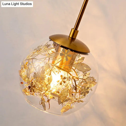 Contemporary brass clear glass wall lamp with foil flower decor featuring a spherical pendant and intricate gold etchings