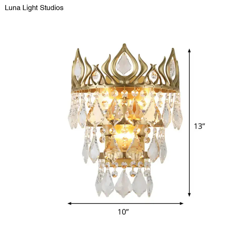 Contemporary brass crown sconce light fixture with gold tone and clear crystal drip for elegant bedroom lighting