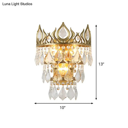 Contemporary brass crown sconce light fixture with gold tone and clear crystal drip for elegant bedroom lighting