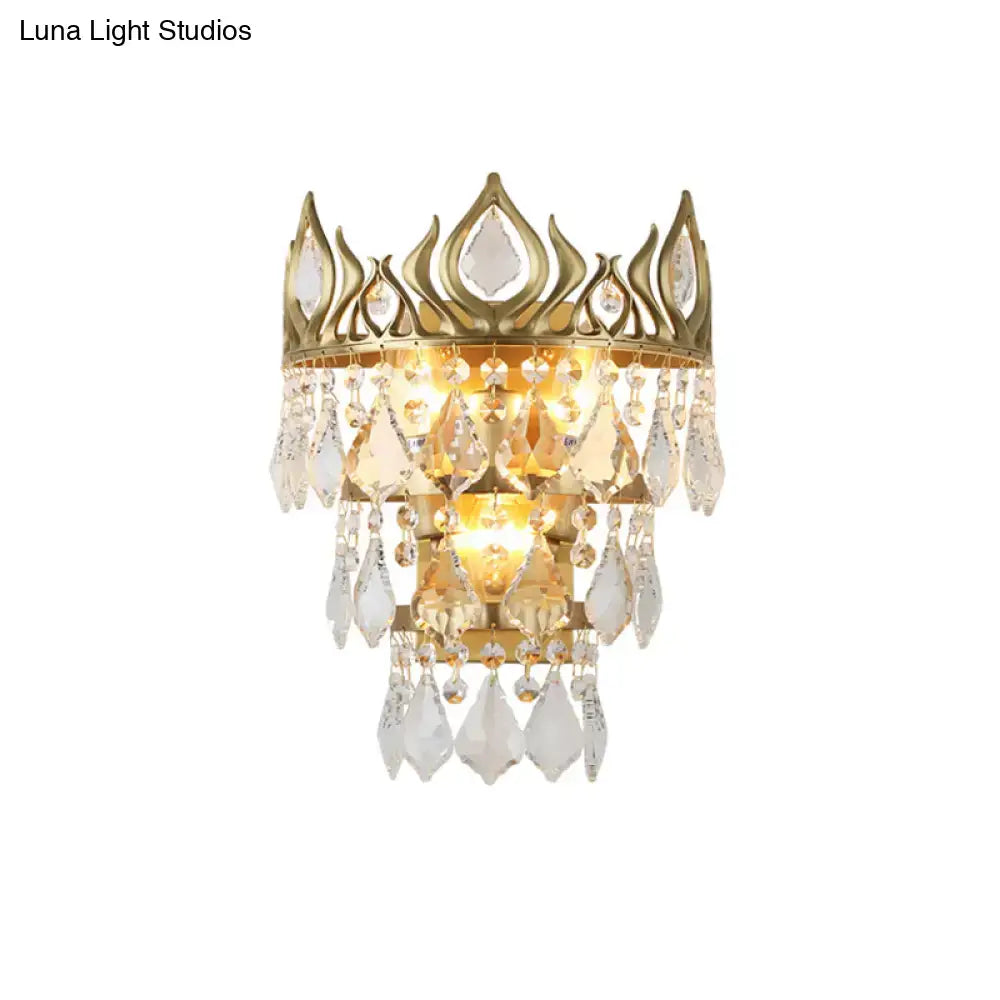 Contemporary brass crown sconce light fixture in gold tone with clear crystal drip accents for bedroom lighting