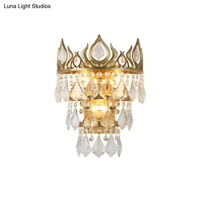 Contemporary brass crown sconce light fixture in gold tone with clear crystal drip accents for bedroom lighting