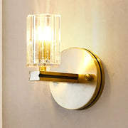 Contemporary brass crystal cylinder sconce light with gold-toned prismatic crystal cylinder shade and circular backplate