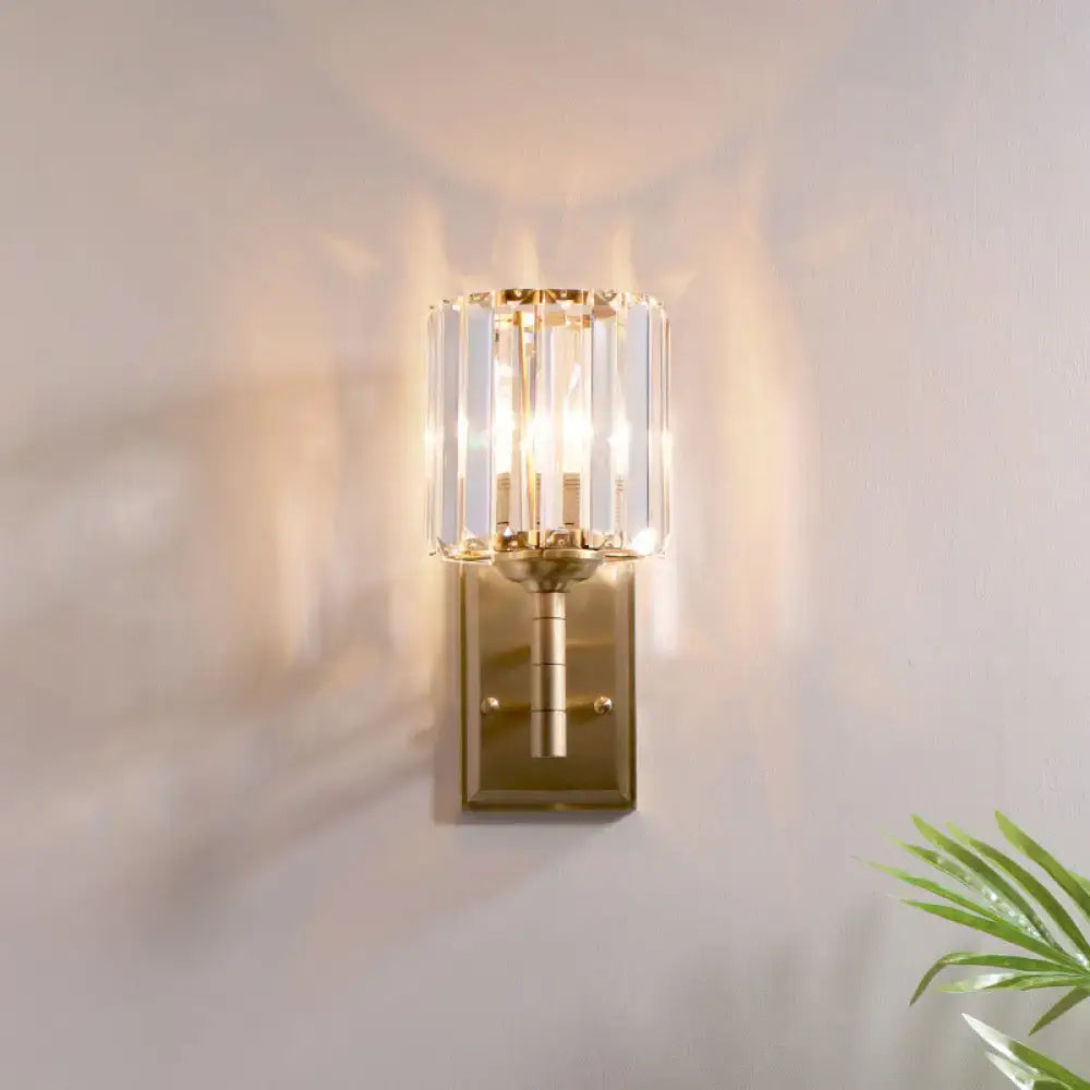 Contemporary brass crystal wall sconce with vertical crystal rods casting warm light for bedroom use