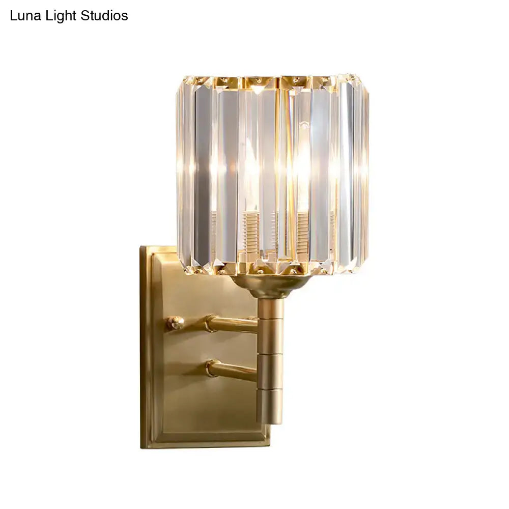 Contemporary brass crystal wall sconce with gold-toned cylindrical shade featuring vertical crystal facets for bedroom lighting